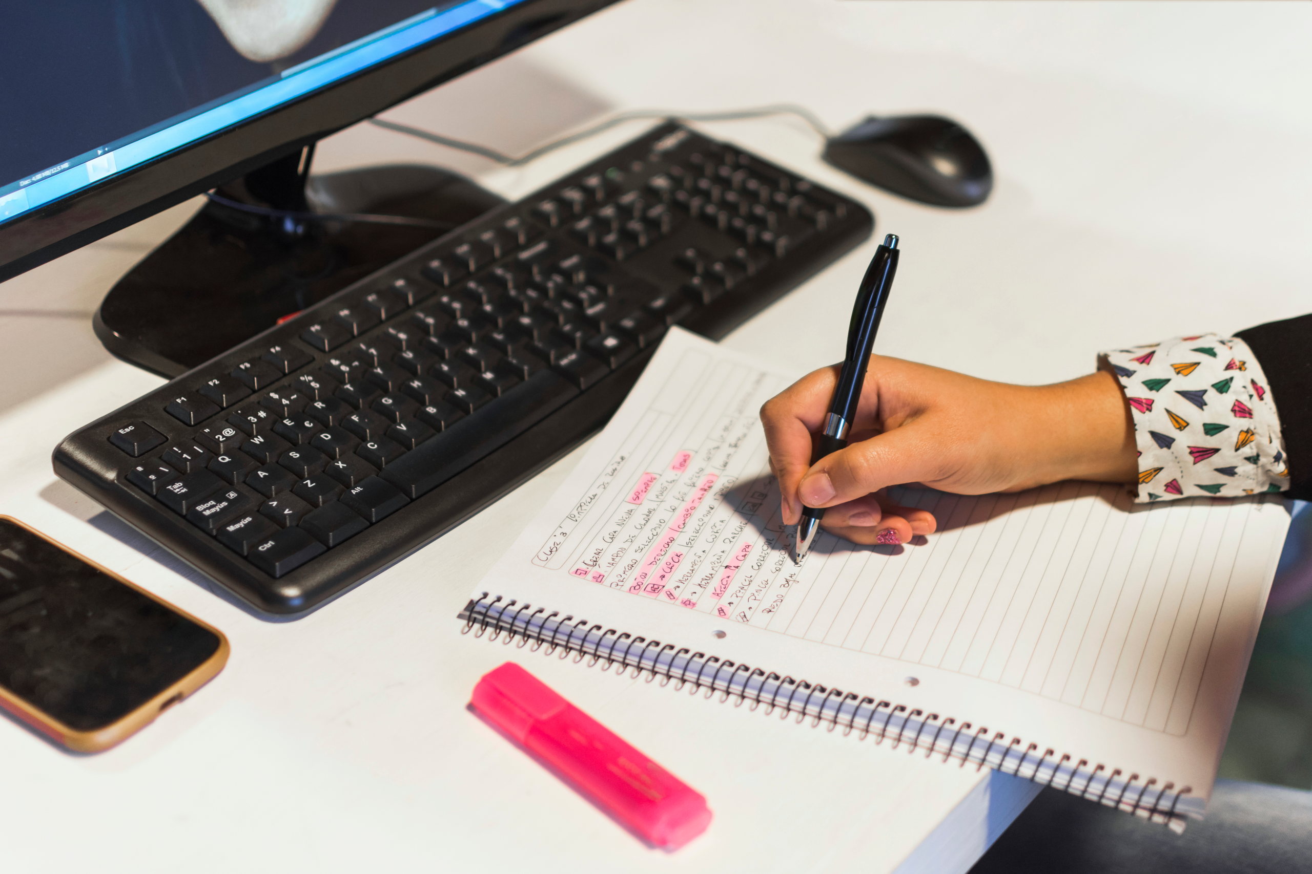 crop-hand-writing-notebook-near-computer